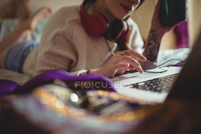 Mulher bonita usando laptop enquanto toma café na cama em casa — Fotografia de Stock