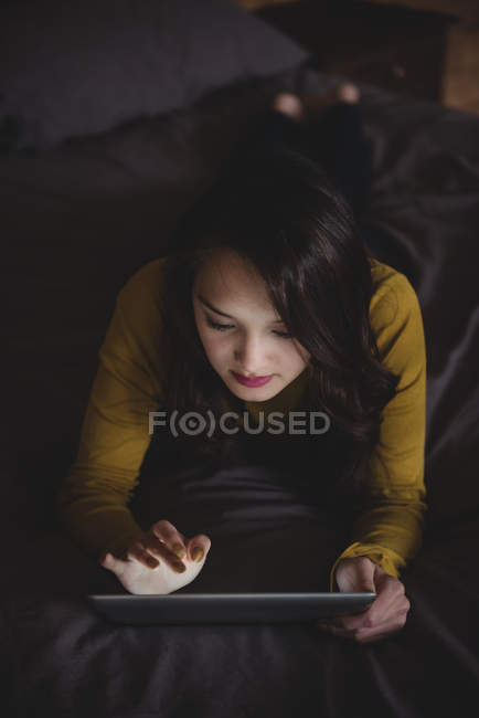 Frau liegt mit digitalem Tablet im heimischen Schlafzimmer im Bett — Stockfoto