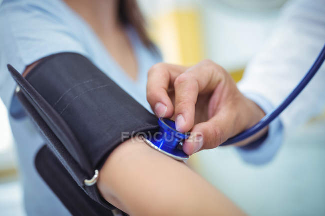 Medico che controlla la pressione sanguigna femminile del paziente in ospedale — Foto stock