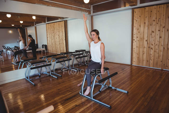 Trainer helping woman while practicing pilates in fitness studio — Stock Photo