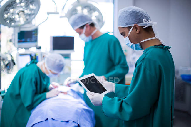 Хирург с помощью цифрового планшета в операционном зале больницы — стоковое фото