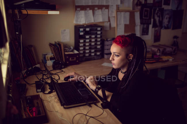 Female hairdresser using laptop in dreadlocks shop — Stock Photo
