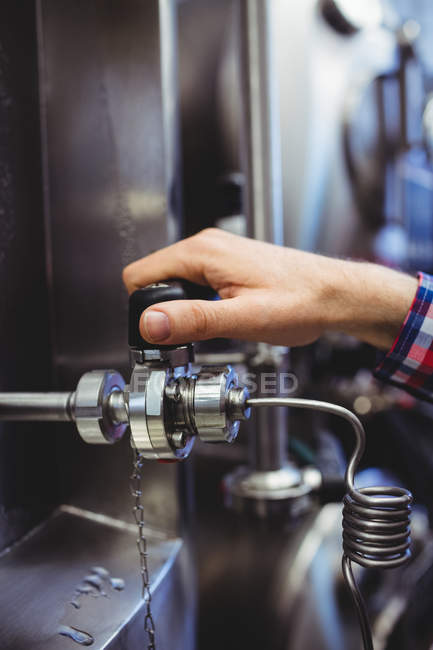 Imagen recortada de la válvula de retención del hombre de la maquinaria en la fábrica de cerveza - foto de stock