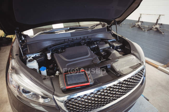 Car with open bonnet and diagnostic device in repair garage — Stock Photo