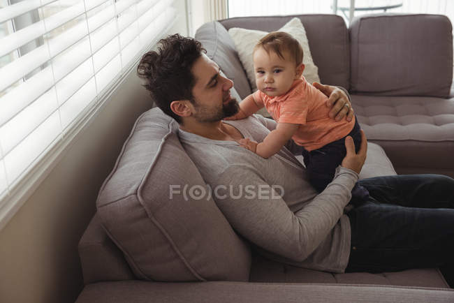 Отец играет со своим ребенком на диване в гостиной дома — стоковое фото