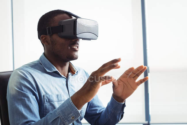Ejecutivo empresarial que utiliza auriculares de realidad virtual en la oficina - foto de stock