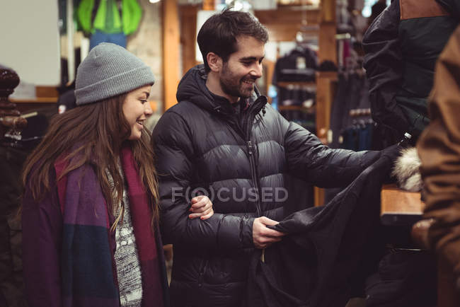 Coppia selezionando abbigliamento insieme in un negozio di abbigliamento — Foto stock