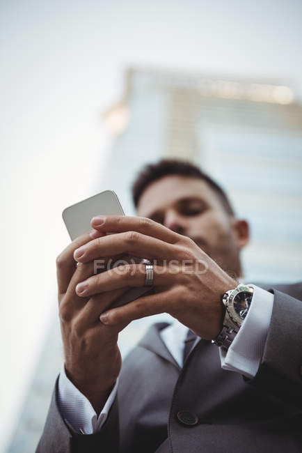 Primer plano de las manos del hombre de negocios utilizando el teléfono móvil cerca del edificio de oficinas - foto de stock