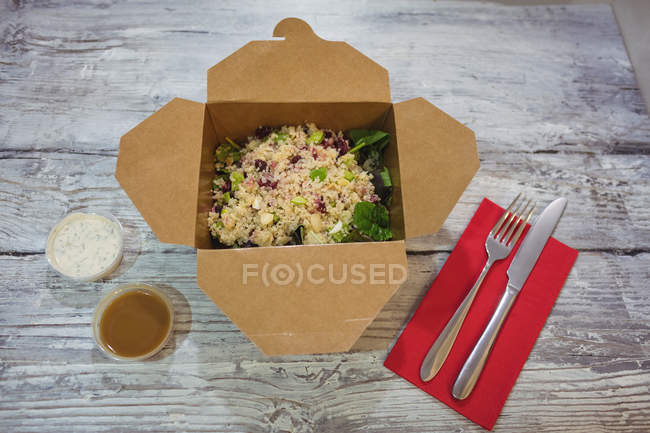 Свежий здоровый салат на деревянном столе с вилкой и ножом — стоковое фото