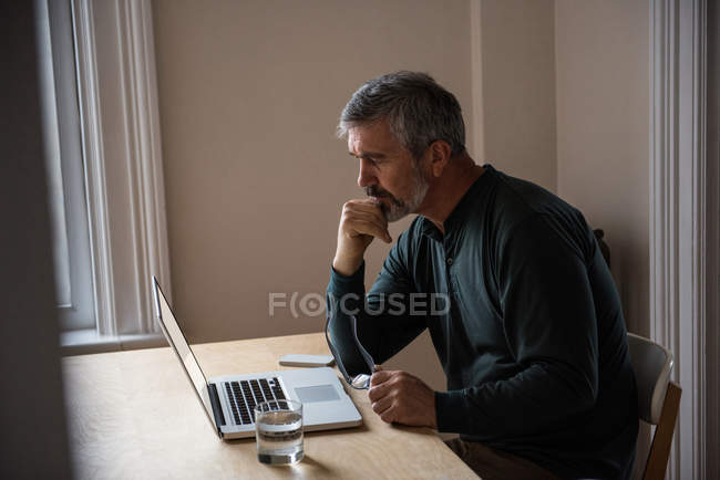 Мужчина сидит с ноутбуком в гостиной дома — стоковое фото