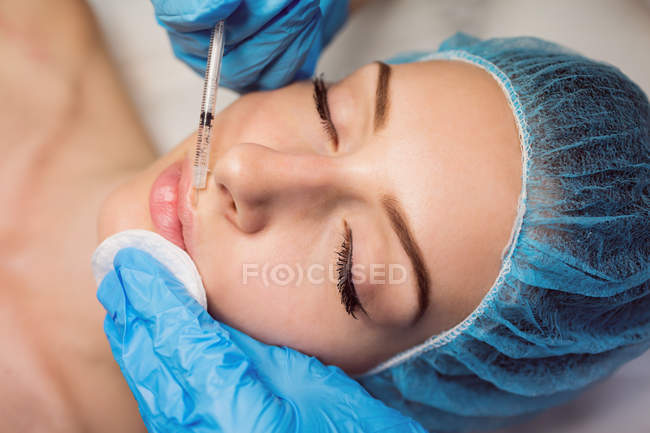 Primer plano de la paciente femenina que recibe inyección facial en la clínica - foto de stock