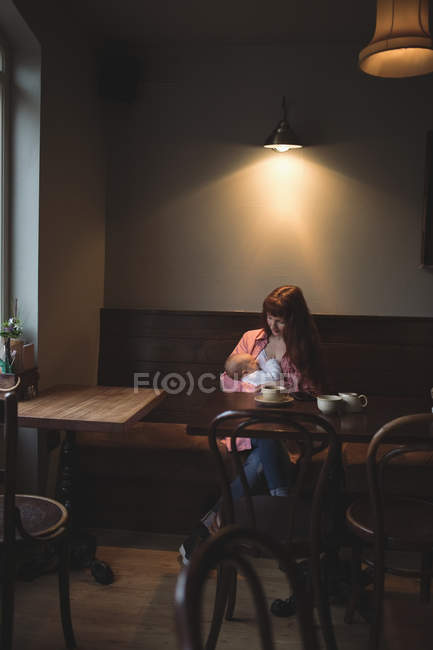 Mother breastfeeding infant daughter in cafe — Stock Photo