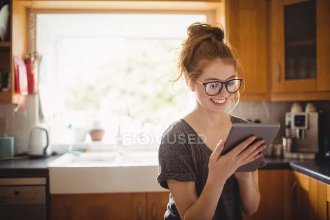 Усміхнена жінка використовує цифровий планшет на кухні вдома — стокове фото