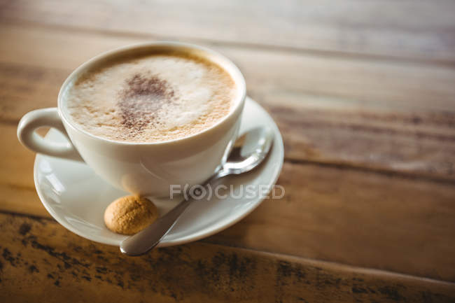Крупный план чашки кофе с блюдцем и ложкой на столе в кафе — стоковое фото