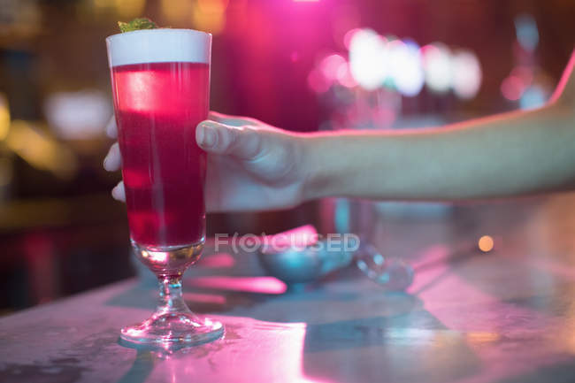Donna che tiene il bicchiere di cocktail rosa in bar — Foto stock