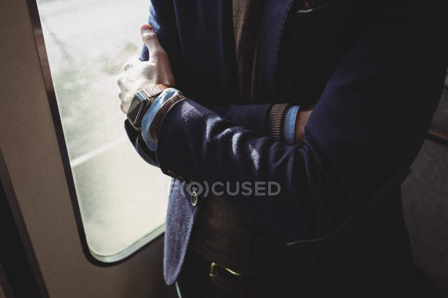 Середній розділ бізнесмена, що стоїть з обіймами, схрещеними в поїзді — стокове фото