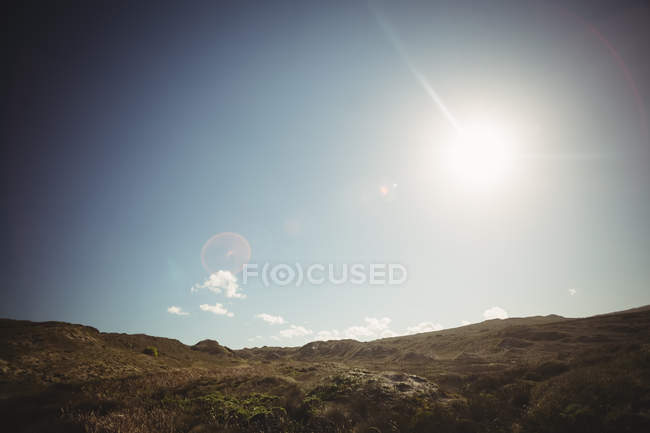 Vista panorâmica da colina sob a luz solar brilhante no céu azul — Fotografia de Stock