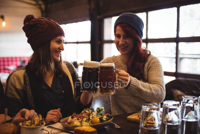 Happy friends toasting with beer glasses in bar — Stock Photo