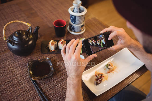 Мужчина фотографирует суши в ресторане — стоковое фото