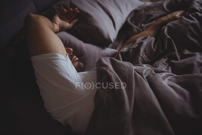 Uomo che dorme a letto in camera da letto a casa — Foto stock