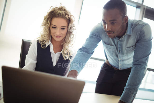 Керівники бізнесу обговорюють ноутбук в офісі — стокове фото