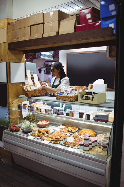 Female staff working at food counter in supermarket — Stock Photo