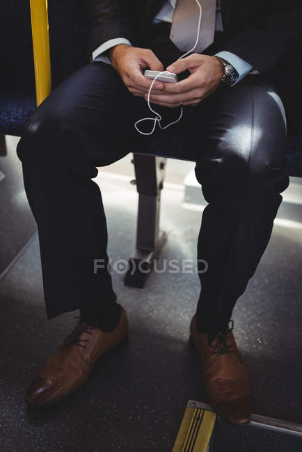 Section basse de l'homme d'affaires en utilisant le téléphone portable tout en voyageant en bus — Photo de stock