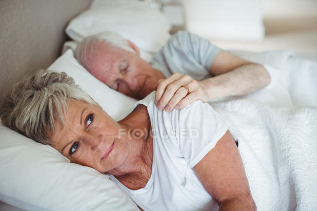 Coppia anziana sdraiata sul letto in camera da letto — Foto stock
