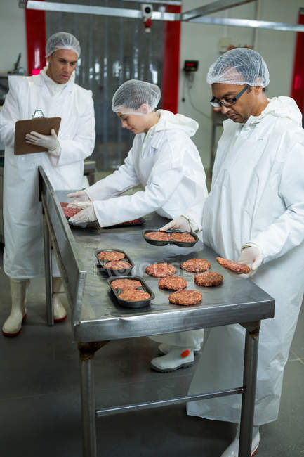 Macellai confezionamento polpette di carne in fabbrica di carne — Foto stock