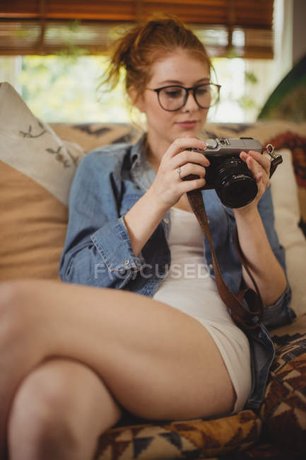 Mujer hermosa mirando fotos en cámara digital en casa - foto de stock
