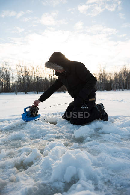 Pescador de gelo pescando em paisagens nevadas e árvores — Fotografia de Stock