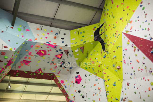 Человек, практикующий скалолазание на искусственной стене в спортзале — стоковое фото