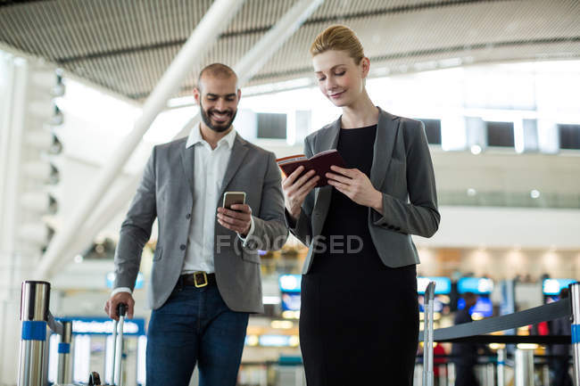 Gente de negocios esperando en cola en un mostrador de facturación con equipaje en la terminal del aeropuerto - foto de stock