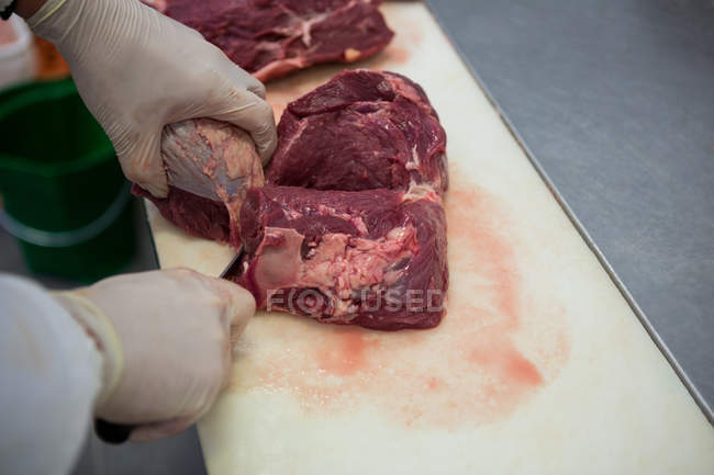 Primer plano de la carnicería que corta carne en la fábrica de carne - foto de stock