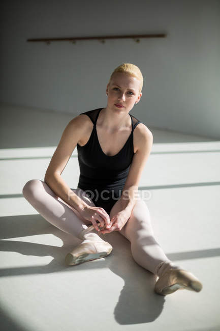 Portrait de ballerine attachant ses chaussures de ballet en studio — Photo de stock