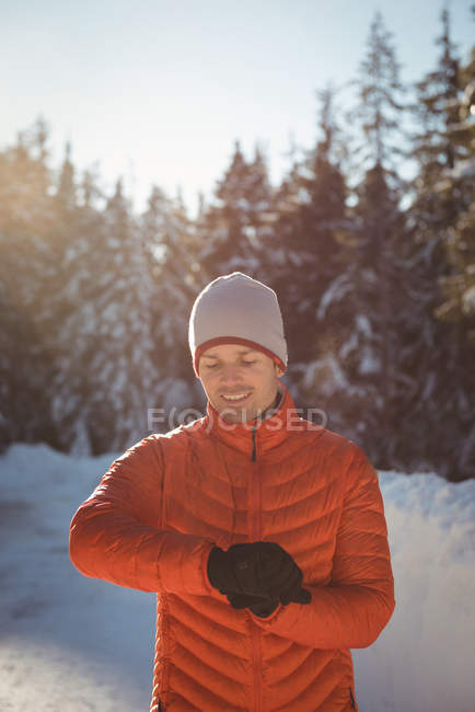 Smiling man adjusting time on smartwatch during winter — Stock Photo