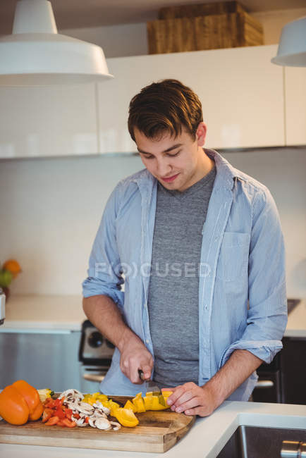 Мужчина режет овощи на кухне дома — стоковое фото