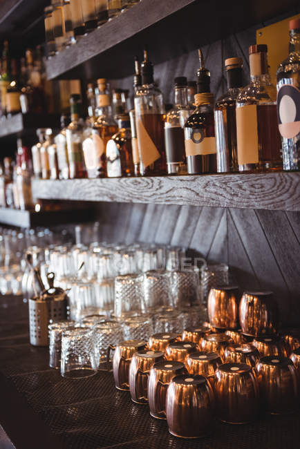 Primo piano di bottiglie e bicchieri disposti su scaffali in un bar — Foto stock