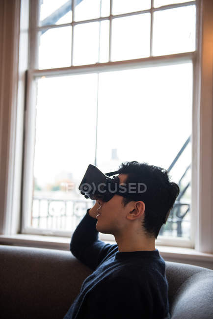 Чоловік використовує гарнітуру віртуальної реальності у вітальні вдома — стокове фото