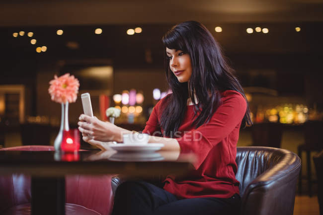 Mujer usando teléfono móvil en restaurante - foto de stock