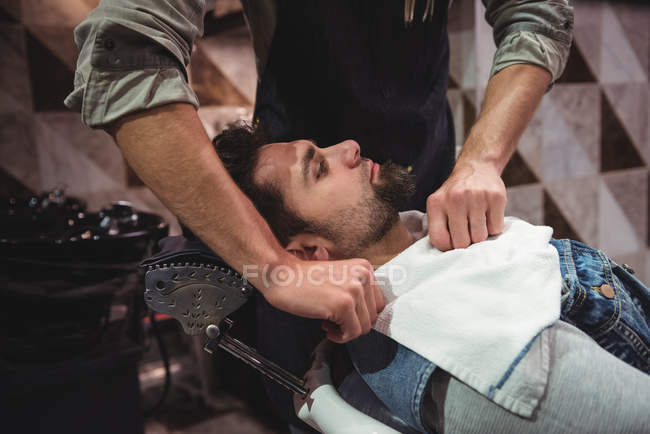 Barbeiro colocando toalha sobre o cliente na barbearia — Fotografia de Stock