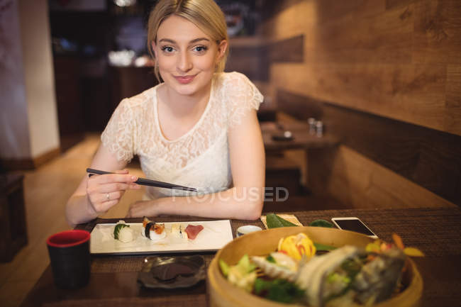 Портрет улыбающейся женщины, поедающей суши в ресторане — стоковое фото