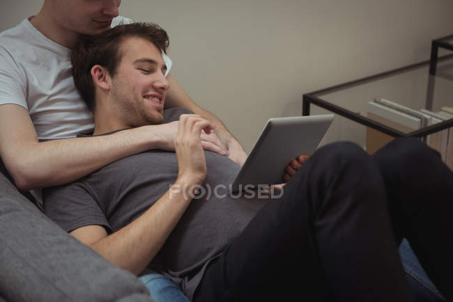 Lächelndes homosexuelles Paar nutzt gemeinsam digitales Tablet zu Hause — Stockfoto