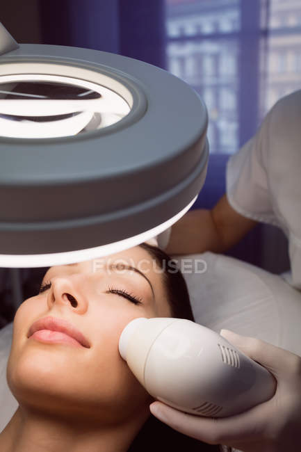 Dermatólogo dando masaje facial al paciente a través de levantamiento sónico en clínica - foto de stock