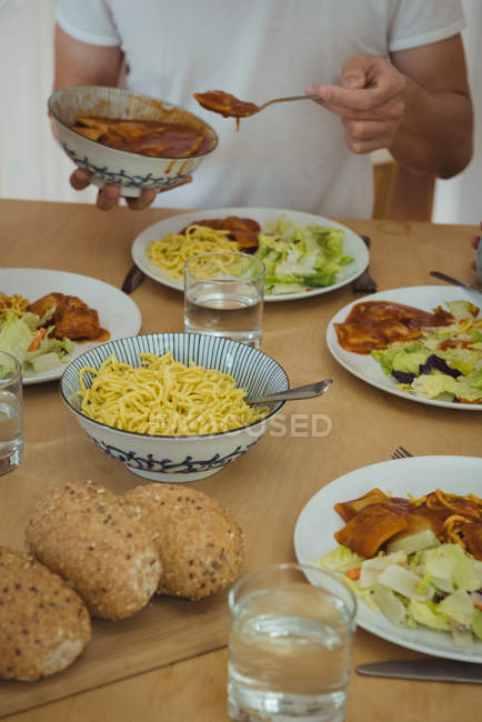 Mittelteil des Menschen, der zu Hause Essen auf dem Esstisch hat — Stockfoto