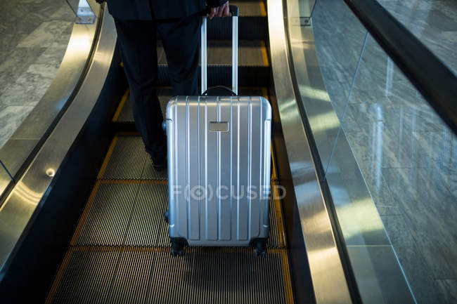 Section basse de l'homme d'affaires sur l'escalier roulant à l'aéroport — Photo de stock