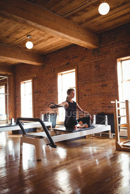 Femme adulte moyenne pratiquant pilates sur réformateur dans un studio de fitness — Photo de stock