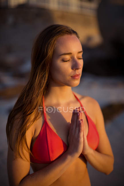 Beautiful woman meditating on beach at dusk — Stock Photo