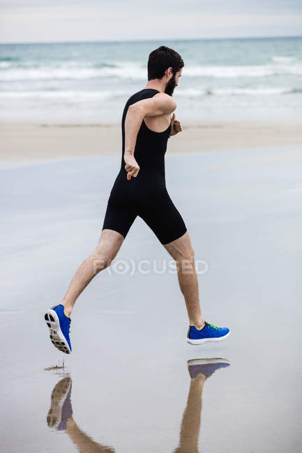 Bonito homem correndo na praia — Fotografia de Stock