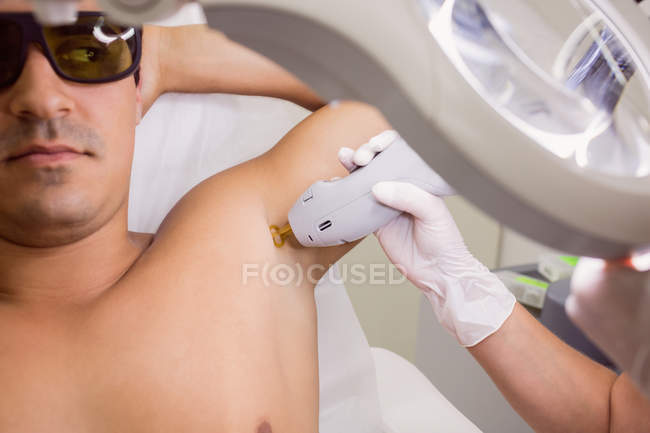 Doctor performing laser hair removal on male patient armpit skin in clinic  — cosmetic, beauty - Stock Photo | #225283376